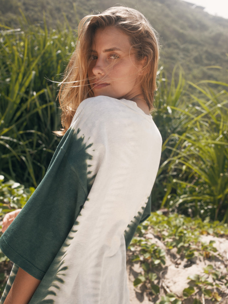 Woman standing in a natural setting with greenery