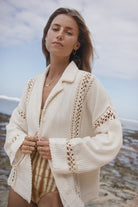 Woman wearing a cream-colored crochet cardigan outdoors 