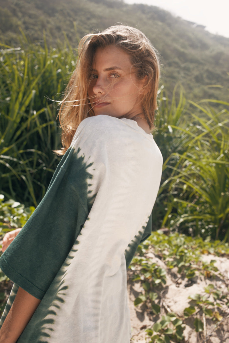 Woman standing in a natural setting with greenery