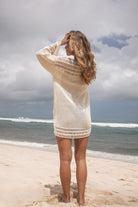 Woman standing on a beach wearing a crochet mini dress 