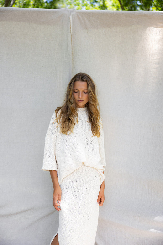 model wearing matching white knit skirt and tee set