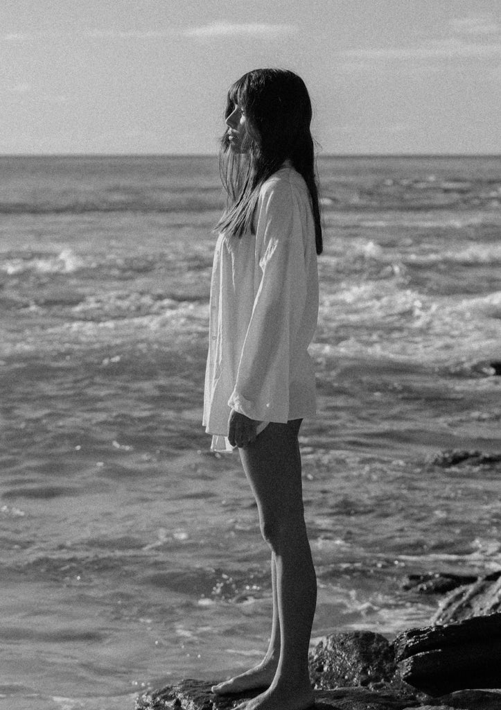 girl looking at ocean standing on rock
