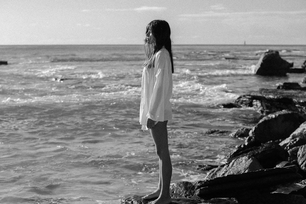 lady standing on rocks looking at ocean